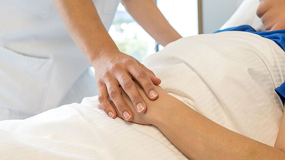 Arzthelferin legt Hände auf die der Patientin.