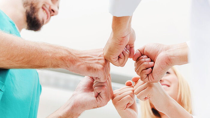 Ein Team bringt die Fäuste zueinander.