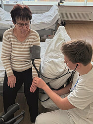 Ein Foto von Pflegefachmann Clemens Reiche, der die Vitalzeichen bei einer Patientin misst.