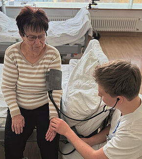 Pflegefachmann Clemens Reiche misst den Blutdruck einer Patientin.